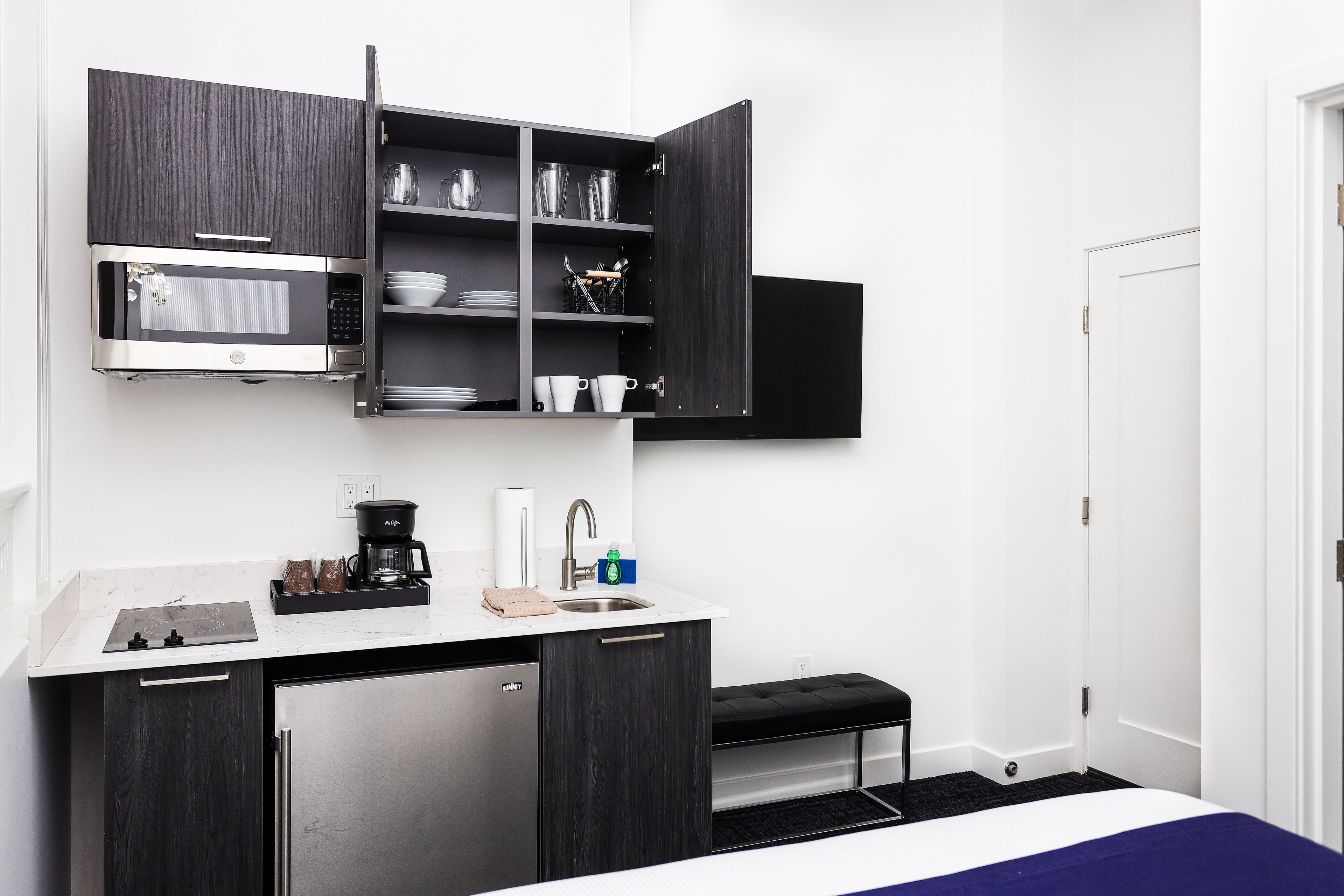 A compact kitchen with a microwave, sink, and storage cabinets.