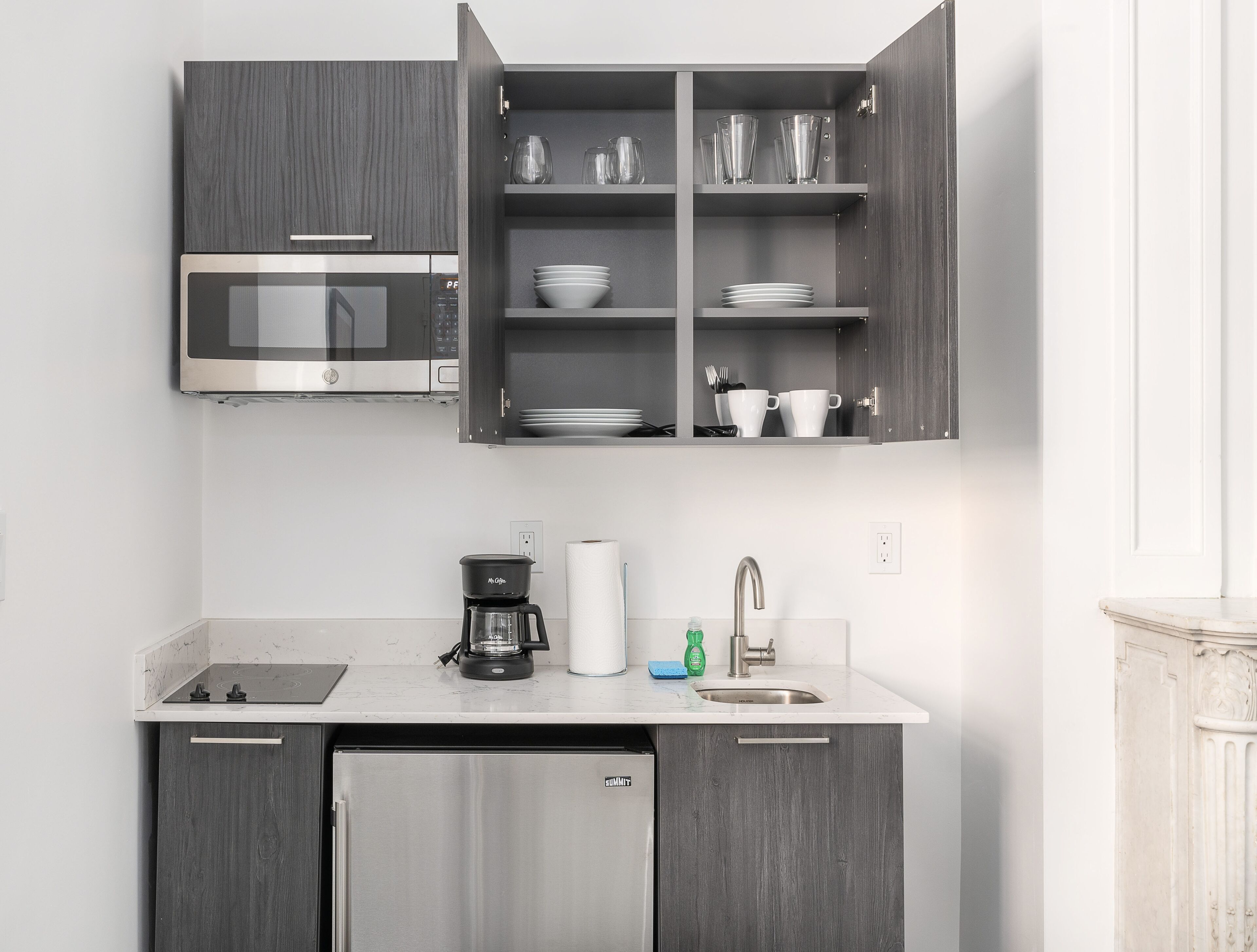 A modern kitchen with a built-in microwave, a coffee maker, a sink, and a refrigerator.