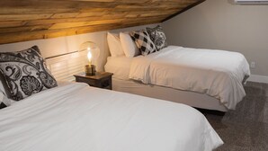 A bedroom with two beds, a nightstand with a lamp, and a wooden ceiling. - Cozy, Spacious, and Right on the Banks of Rocky Creek, Two Creeks Crossing Resort (Livingston)