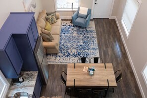 A modern living room with a sofa, a blue armchair, a wooden dining table, and a patterned rug.
