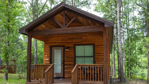 Une cabane en bois avec une véranda, une porte et une fenêtre.