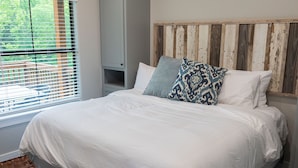 A bedroom with a large bed, a wooden headboard, and a window with blinds. - A Cozy Getaway Right on the Water, Two Creeks Crossing Resort (Livingston)