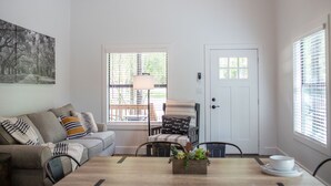 A dining area with a wooden table, chairs, a bench, a sofa, and a door with a window. - Cozy, Spacious, and Right on the Banks of Rocky Creek, Two Creeks Crossing Resort (Livingston)