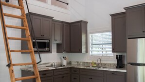 A kitchen with dark cabinets, a microwave, a coffee maker, and a window with blinds. - Cozy, Spacious, and Right on the Banks of Rocky Creek, Two Creeks Crossing Resort (Livingston)