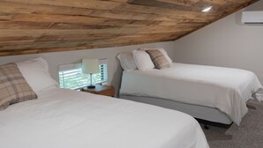 Une chambre avec deux lits, une table de chevet avec une lampe et un plafond en bois.