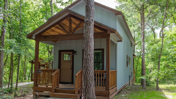Une cabane avec une véranda, une porte et une fenêtre.
