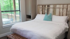 Un dormitorio con una cama grande, cabecera de madera, un banco y una ventana con persianas.