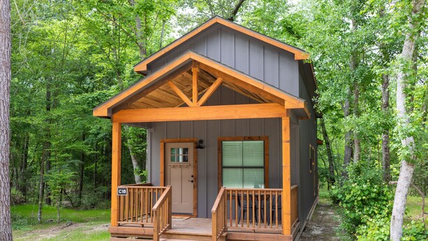 Une cabane avec une véranda en bois, une porte et une fenêtre.
