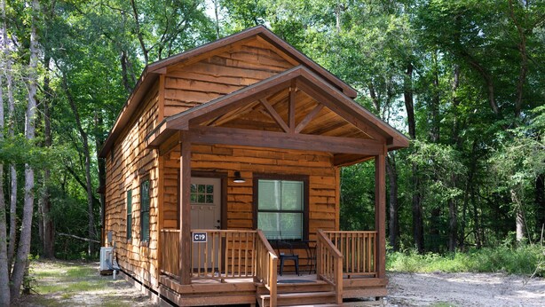 Une cabane en bois avec une véranda, une porte et une fenêtre.