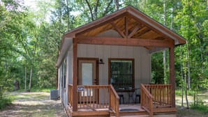 Une cabane en bois avec une véranda, une porte et une fenêtre.