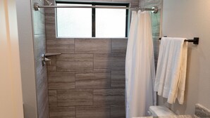 Een badkamer met een douchegedeelte, een stenen muur en een toilet met een marmeren blad.