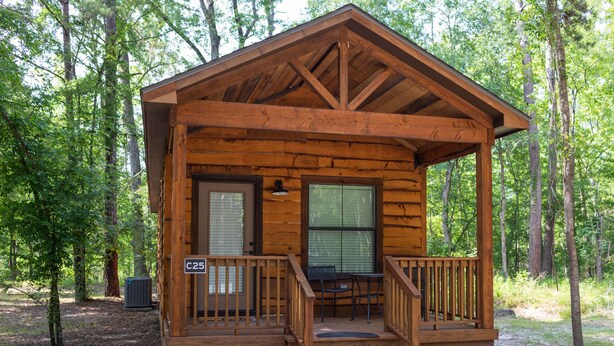 Een houten chalet met een veranda, een deur en een raam.