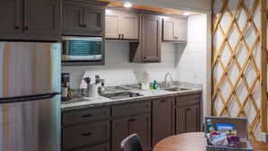A compact kitchen with a refrigerator, microwave, sink, and a dining area with a table and chairs. - Close to nature, but with all the modern amenities, Two Creeks Crossing Resort (Livingston)