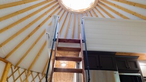 A high ceiling with wooden beams and a skylight, a wooden ladder, and a kitchen area with cabinets and appliances. - Close to nature, but with all the modern amenities, Two Creeks Crossing Resort (Livingston)
