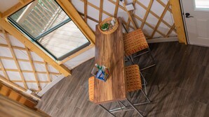 A wooden dining table with four chairs, a window, and a door in a room with a sloped ceiling and wooden beams. - Close to nature, but with all the modern amenities, Two Creeks Crossing Resort (Livingston)