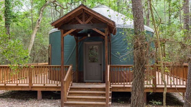A yurt with a wooden porch and steps leading to a door. - Close to nature, but with all the modern amenities, Two Creeks Crossing Resort (Livingston)