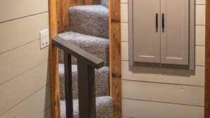 A staircase with wooden steps and a handrail, leading to a room with a white door and a ceiling light. - Close to nature, but with all the modern amenities, Two Creeks Crossing Resort (Livingston)