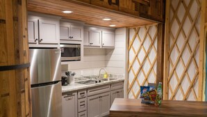 A kitchen with white cabinets, a stainless steel refrigerator, a microwave, and a sink. There is a table with snacks and a patterned cushion. - Close to nature, but with all the modern amenities, Two Creeks Crossing Resort (Livingston)