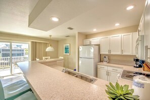 A modern kitchen with a large island, white cabinets, and a built-in dishwasher.