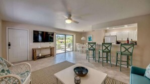 Un espacio habitable amplio con televisor, una mesa de comedor con sillas, una zona de cocina y un balcón con vistas.