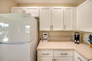 A kitchen with white cabinets, a white refrigerator, a coffee maker, and a Keurig coffee maker.