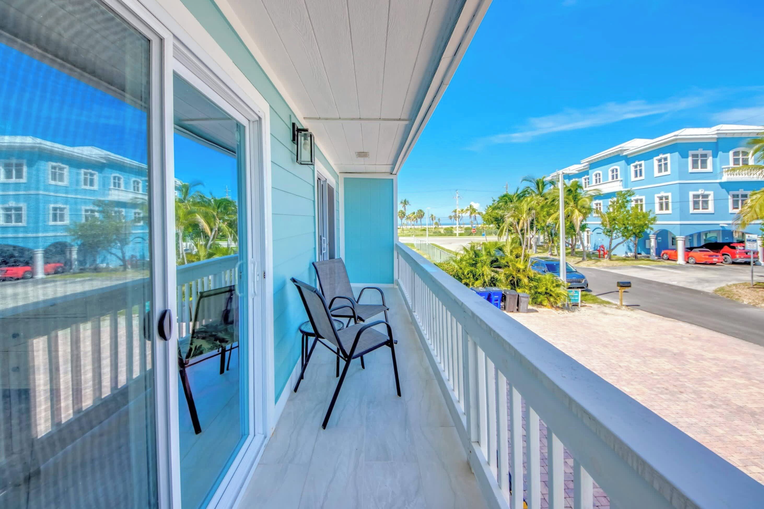 A balcony with a view of a blue building and palm trees.