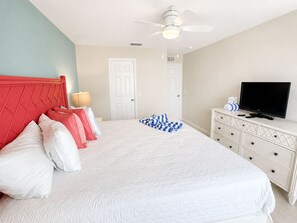 A bedroom with a bed, a television, a dresser, and a ceiling fan. - 110 Bahia #4 Pet Friendly Canal Unit with Pool (Fort Myers Beach)