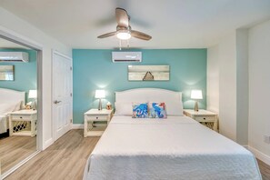 A bedroom with a bed, two bedside tables, a ceiling fan, an air conditioning unit, and a wall-mounted picture. - 110 Bahia #1 Pet Friendly Canal Unit with Pool (Fort Myers Beach)