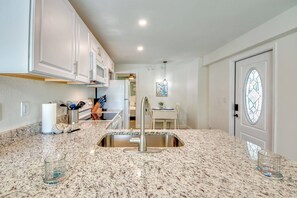 A kitchen with granite countertops, stainless steel appliances, and a white cabinet.