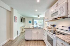 A modern kitchen with white cabinetry, a built-in microwave, and a stainless steel oven.