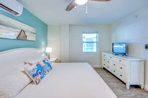 Un dormitorio con cama, cómoda, televisor y ventana.