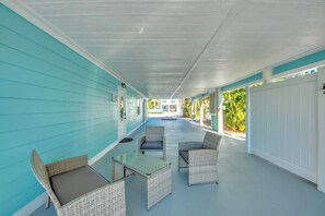 A covered porch with wicker furniture and a glass-top table. - 110 Bahia #1 Pet Friendly Canal Unit with Pool (Fort Myers Beach)