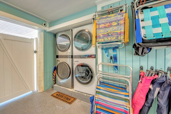 A laundry area with four washing machines, a drying rack, and a wall-mounted drying rack with colorful towels.