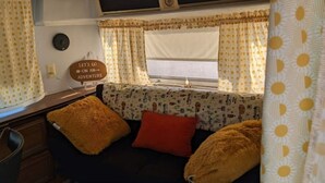 A cozy RV interior with a sofa bed, a red pillow, and a 'Let's go on an adventure' sign. - Silver Sun Retreat (Dover)