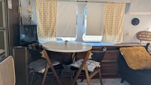A compact RV interior with a dining area, a small kitchenette, and a cozy seating arrangement. - Silver Sun Retreat (Dover)