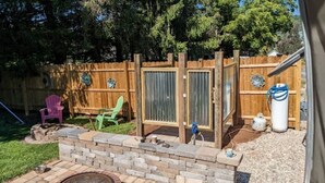 A backyard with a wooden fence, a brick fire pit, and two green chairs. - Silver Sun Retreat (Dover)