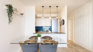 Et moderne køkken med hvide skabe, blå backsplash og en central ø med et køleskab.