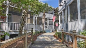 A wooden pathway leading to a building with multiple balconies and an American flag. - Family Beach Escape | 3 Pools, Hot Tub & Gulf Beaches Nearby (Port St. Joe)