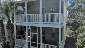 A two-story house with a balcony, a porch, and a small outdoor area with palm trees. - Family Beach Escape | 3 Pools, Hot Tub & Gulf Beaches Nearby (Port St. Joe)