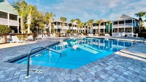 A swimming pool with lounge chairs and a three-story building with balconies. - Family Beach Escape | 3 Pools, Hot Tub & Gulf Beaches Nearby (Port St. Joe)