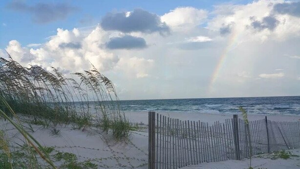 A beach with a wooden fence, sea grass, and a rainbow in the sky. - Family Beach Escape | 3 Pools, Hot Tub & Gulf Beaches Nearby (Port St. Joe)