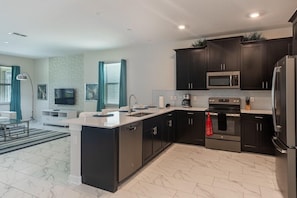 Enjoy cooking in this well-equipped kitchen with a large island, sink, and stainless steel appliances.