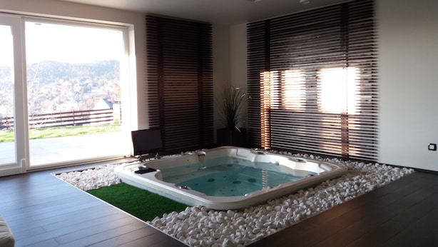 A modern bathroom with a large bathtub, a shower area, and a view of a residential area through large windows.