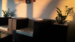 A room with a sofa and two side tables, a wall-mounted artwork, and two potted plants.