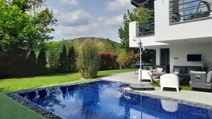 A modern house with a swimming pool, outdoor furniture, and a well-maintained garden.