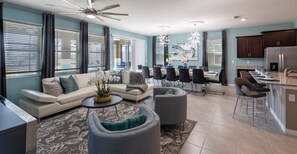Relax in a spacious living area with a sofa, armchairs, and dining table for six, plus a fully equipped kitchen with an island.