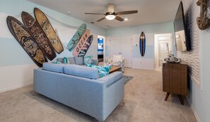 Relax in this stylish living room with a sofa, surfboard decor, and a large mirror.