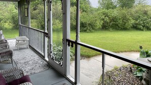 En overdækket veranda med fletmøbler og udsigt til en græsplæde.