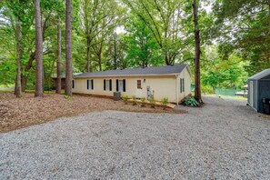 A single-story mobile home with a gravel driveway, surrounded by trees. - Hillside LKN - Lakefront - Priv Dock, Family Fun - Lake Norman Vacation Rental (Mooresville)