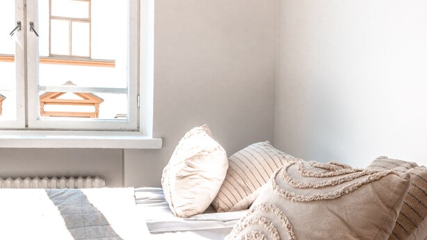 A bedroom with a bed, pillows, a window, and a radiator. - 2ndhomes Modern Studio close to the Sea (Helsinki)